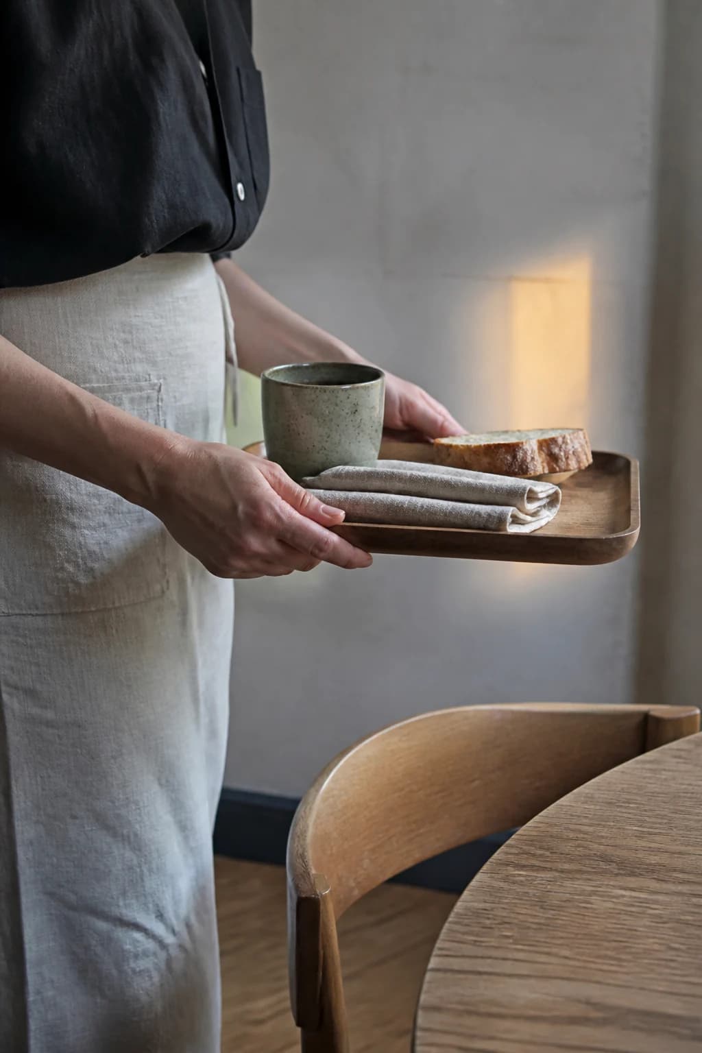 Una persona del equipo lleva café y pan hacia una mesa.